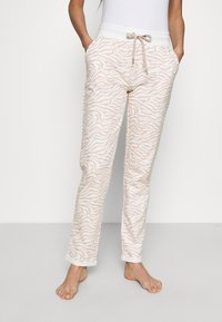 Lichtroze trainingsbroek met een wit zebra-streep patroon, voorzien van een elastische tailleband, trekkoord en zijzakken. Zachte textuur.