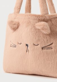 Mäkká ružová chlpatá kabelka s výšivkou mačacej tváre, so zatvorenými očami, fúzmi a dvomi plyšovými ušami na vrchu blízko rúčok.