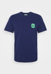 Navy blue cotton t-shirt with round neck, short sleeves, and a green embroidered logo patch featuring a crocodile and "CLUB."