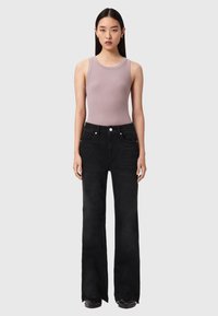 Sorte jeans med vide ben lavet af denim med høj talje, der har forlommer og en diskret falmet effekt. Kombineret med en lilla ærmeløs top.