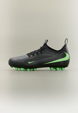 Čierna futbalová kopačka so zelenými kolíkmi a logami Nike, šnurovanie a ťahacie pútka na päte a jazyku.