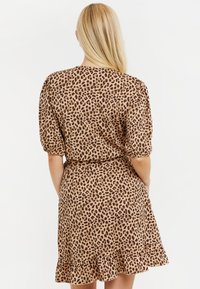 Šaty s leopardím potiskem v hnědých tónech, lehká látka, nařasené rukávy, elastický pas a volánkový lem. Zadní pohled ukazuje detaily designu.