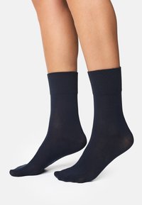 Mørkeblå ankelstrømper lavet af blødt materiale med ribbet kant. Glat tekstur, tætsiddende design og forstærket tåområde synligt.