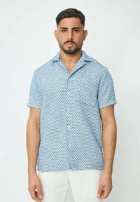 Chemise à manches courtes en bleu clair, avec un motif géométrique. Fabriquée en tissu léger au toucher doux.