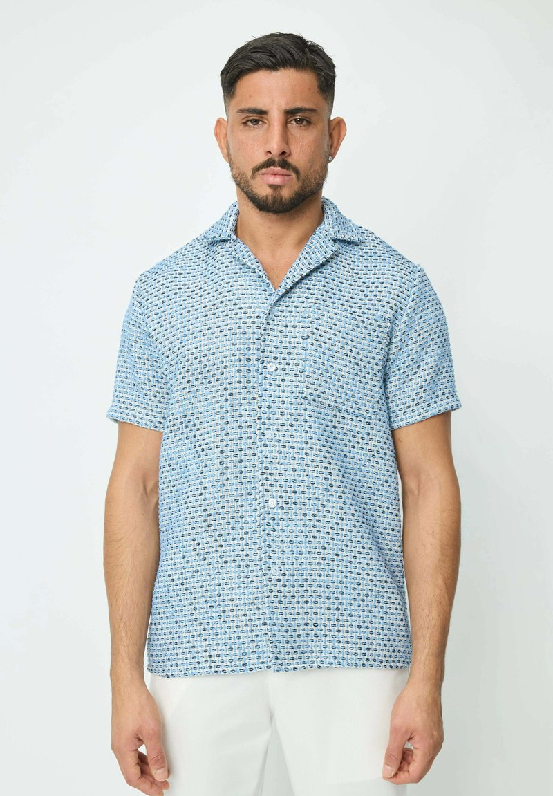 Chemise à manches courtes en bleu clair, avec un motif géométrique. Fabriquée en tissu léger au toucher doux.