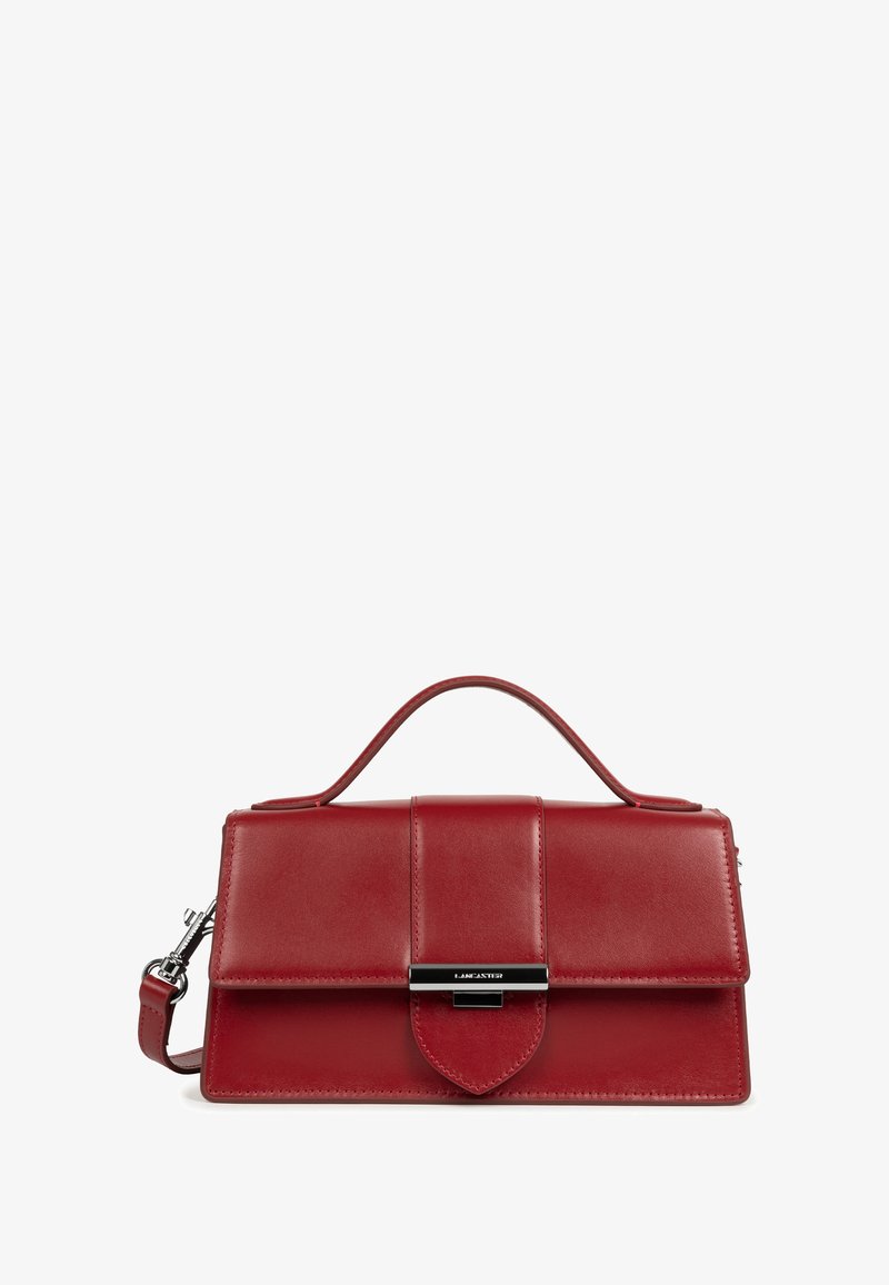 Rote Lederhandtasche mit Obergriff, vorderer Klappe und silberfarbener Metallschließe mit graviertem Lancaster-Logo, isoliert auf weißem Hintergrund.