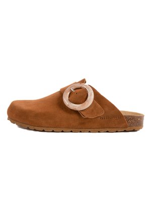 Chaussure slip-on en daim marron avec une large sangle, boucle en acrylique transparente ronde et semelle en liège texturé. Présente une légère élévation au talon.