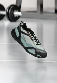 Ελαφρύ αθλητικό παπούτσι με διαφανές πράσινο μέντας και μαύρο σχέδιο, με υφασμένο πάτο, μαξιλαρωμένη υποστήριξη αστραγάλου και μαύρα κορδόνια.