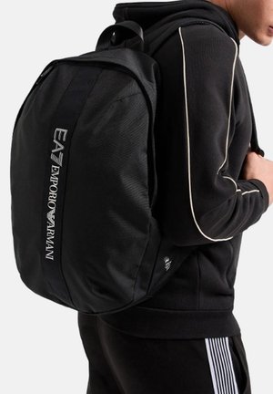 Zaino nero realizzato in tessuto resistente, dotato di un ampio scomparto principale, texture morbida e logo ricamato EA7 Emporio Armani.