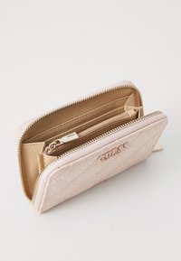 Quilted pink wallet with gold zipper, featuring multiple compartments and a small zip pocket inside, embossed logo on the exterior.