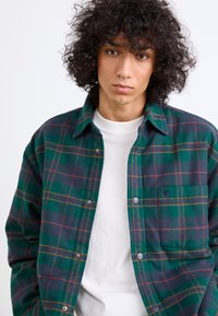 Zöld és tengerészkék kockás flanel ing narancssárga akcentussal, gombos kialakítással és mellzsebbe. Puha tapintás és formázott gallér.