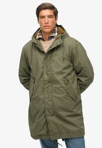 Olive green hooded parka jacket with a zip-front, drawstring waist, and two side pockets. Soft texture, featuring a fur-lined collar.