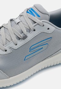 Light grey athletic shoe with mesh and synthetic material, featuring blue accents, round laces, and textured sole for grip.