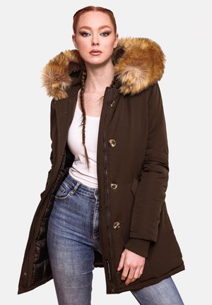 Brown parka with fur-lined hood, gold buttons, two front pockets, and a zip closure. Worn over a white top and blue jeans.