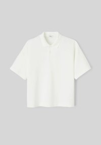 Polo shirt blanc avec un col classique, des manches courtes et une coupe décontractée. Fabriqué en tissu en coton doux, avec une patte de boutonnage à trois boutons.