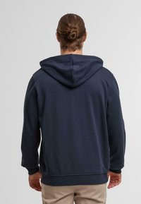 Navy blue hoodie with a adjustable drawstring hood, ribbed cuffs and hem, made from a soft fabric, featuring a plain texture.