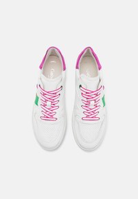 Vita lädersneakers med rosa snören och detaljer. Har en grön sidologga, perforerat tånärområde och vadderad krage för komfort.