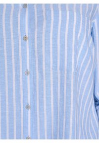 Camicia azzurra chiara con bottoni, caratterizzata da strisce verticali bianche, taschino sul petto e texture liscia con dettagli dei bottoni a contrasto.
