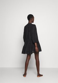 Black embroidered mini dress with long puff sleeves, gathered tiers, and eyelet detailing. Lightweight fabric with a relaxed fit.