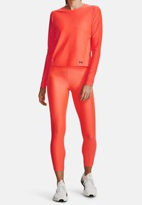 Klart neonorange långärmad topp och matchande leggings gjorda av ett slätt, stretchigt tyg, med en figurnära passform och logodetaljer.