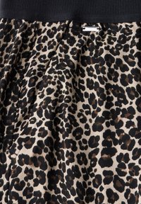 Leopard print fabric with beige background and black/brown spots. Features a black ribbed waistband and tag with "StreetOn" label.