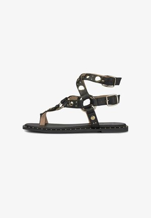 Platte zwarte sandaal met meerdere enkelbandjes, gouden gespen en metalen studs versieringen op de bandjes en de rand van de zool.