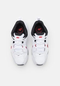 White Nike sneakers featuring black accents, red branding, and a textured upper. Lace-up design with a padded interior for comfort.