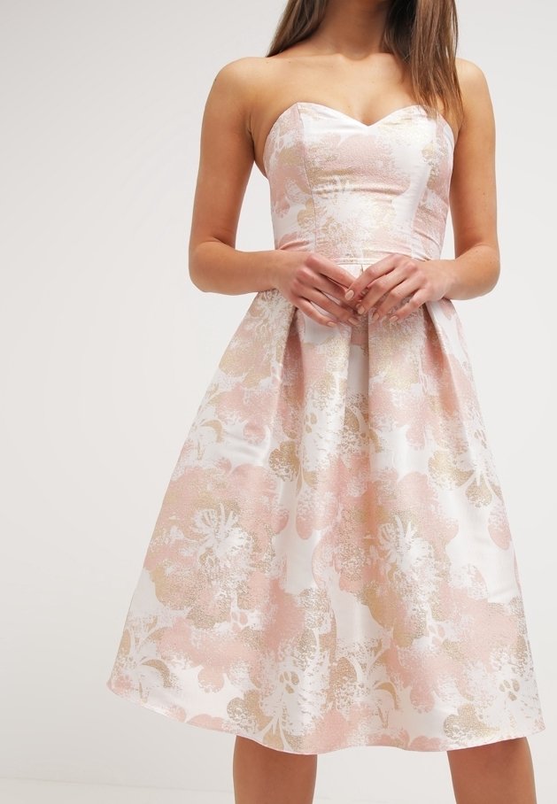 Robe bustier en brocart floral rose et or avec corsage ajusté et jupe plissée en ligne A portée par une femme aux longs cheveux.