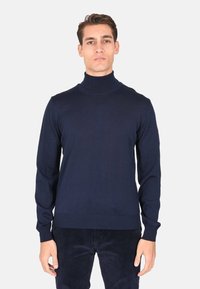 Maglione a collo alto blu navy realizzato in tessuto a maglia liscia. Maniche lunghe aderenti e colletto e orlo a costine. Design semplice, senza motivi o accenti.