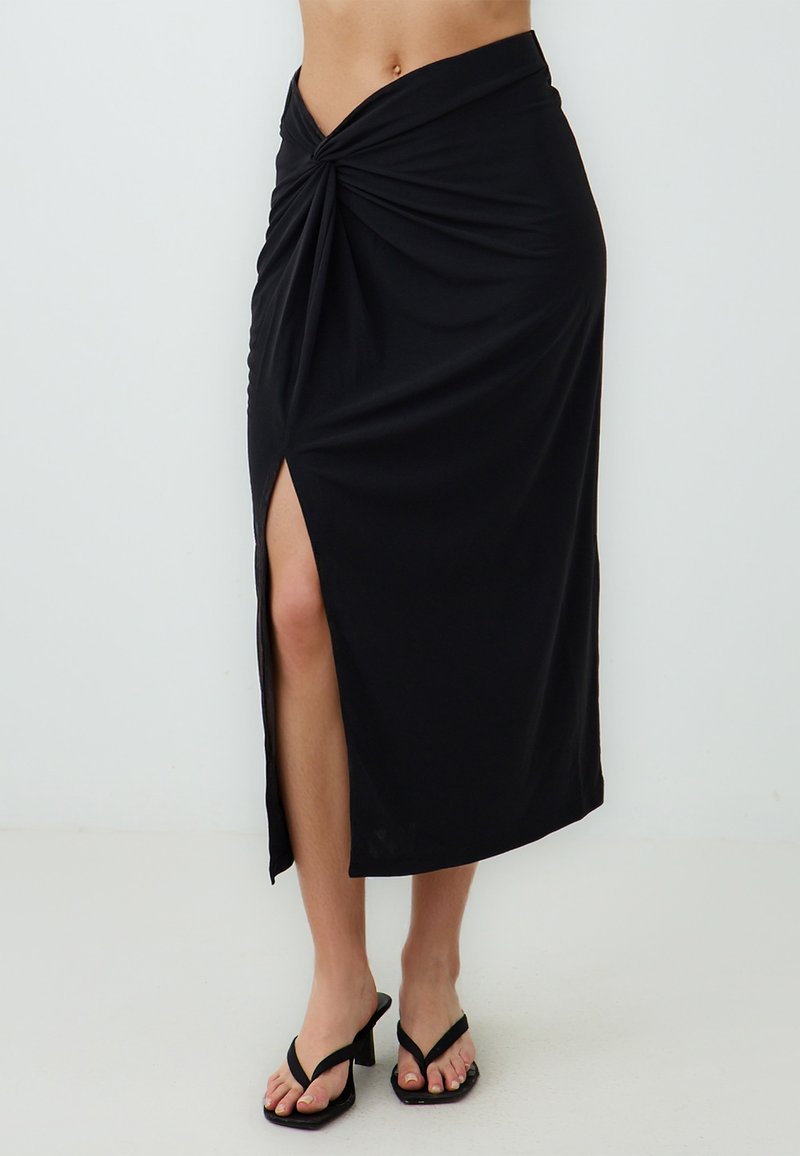 Zwarte maxi-jurk van gladde stof, met een gedraaide knoopdetail bij de taille en een split aan de voorkant voor extra beweging.