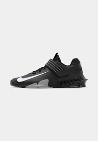 Baskets de sport noires au design épuré, avec un logo Nike blanc bien en vue, des surcouches texturées et une semelle moulée distincte.