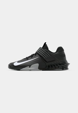 Schwarze Sportschuhe mit einem eleganten Design, ausgestattet mit einem auffälligen weißen Nike-Logo, strukturierten Overlay und einer markanten, geformten Sohle.