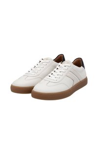 Sneakers bianchi in pelle con finitura testurizzata, caratterizzati da suole in gomma marrone, lacci crema e un accento nero sul tallone. Design classico low-top.