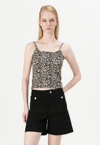 Leopardmønster tanktop med smale stropper, sammen med høytlivs svarte shorts med gullknapper og frontlommer.