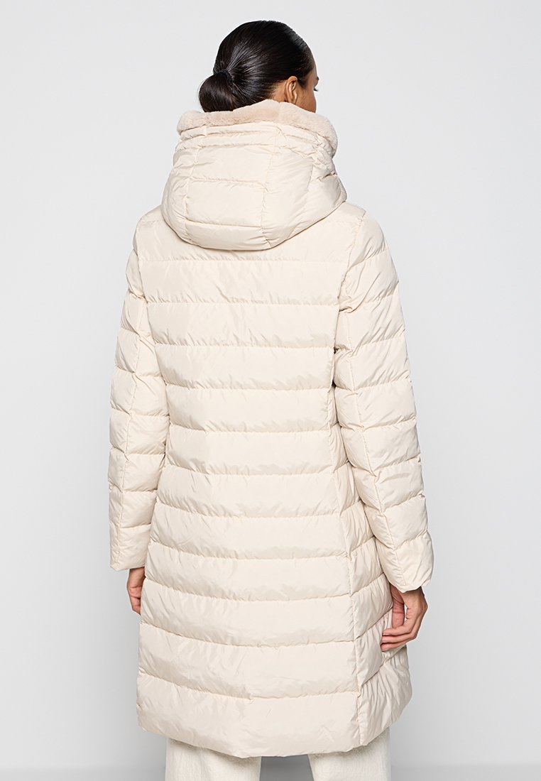 Jasnobeżowy puchowy płaszcz z wysokim kołnierzem, pikowany wzór i długie rękawy. Posiada kaptur i sięga do połowy uda.
