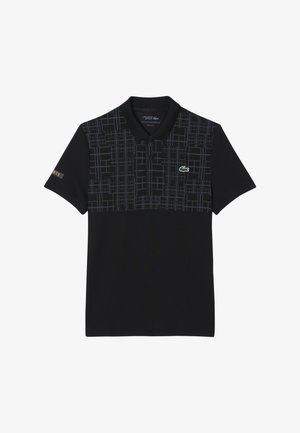 Polo shirt Lacoste nera con un motivo geometrico grigio sul petto e il logo del coccodrillo verde del marchio sul lato sinistro.