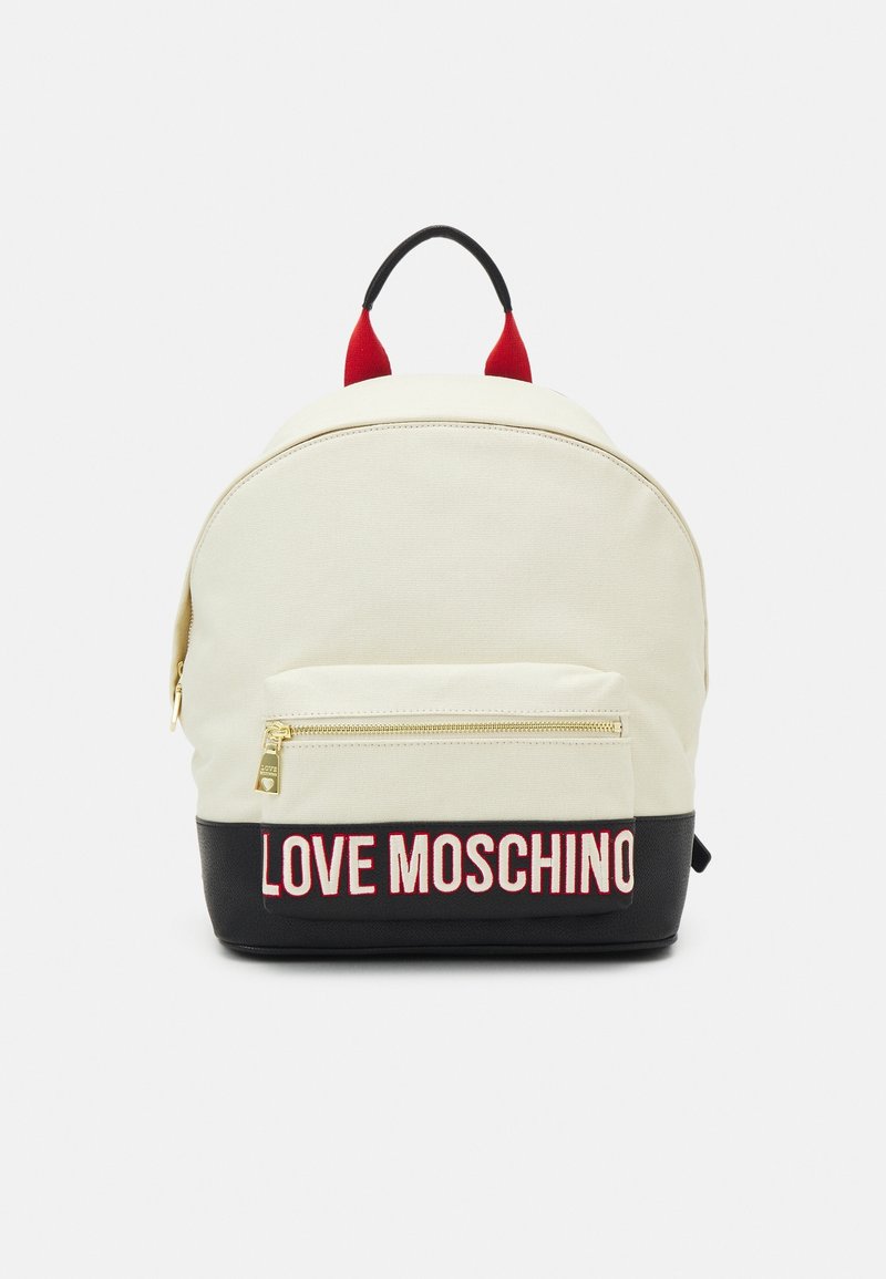 Sac à dos en toile crème avec une base noire. Il dispose d'une poche avant avec une fermeture éclair dorée et "LOVE MOSCHINO" en lettres rouges. Poignées supérieures rouges.