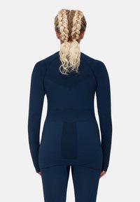 Haut de sport à manches longues bleu marine avec une coupe ajustée, texture lisse et coutures stratégiques, associé à un bas ajusté assorti.