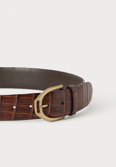 Ceinture en cuir marron avec motif crocodile et boucle en métal doré, posée à plat sur une surface blanche.