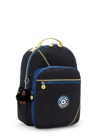 Zaino in nylon nero con accenti gialli, cerniere blu e una finitura testurizzata. Presenta un portachiavi a forma di scimmia e una patch logo rotonda.