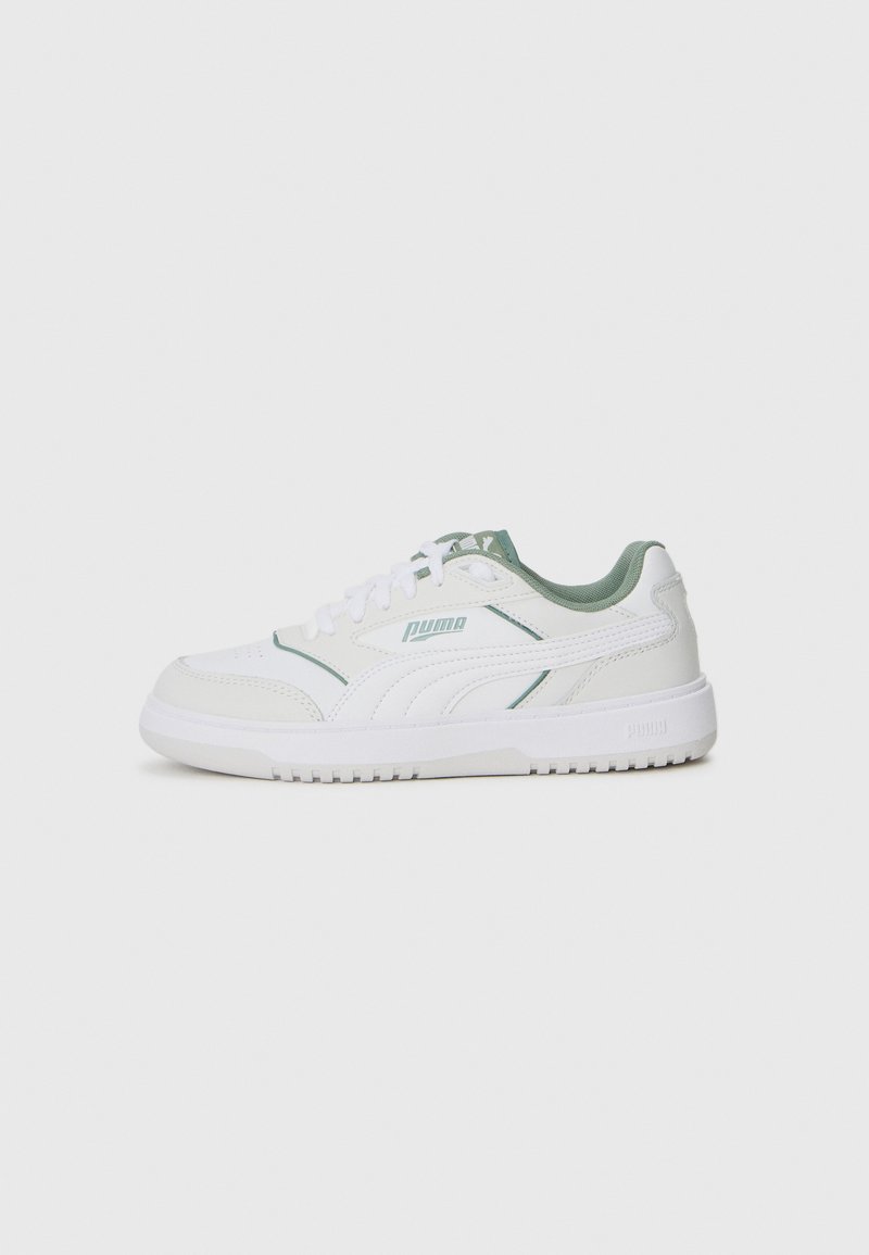 Sneaker bianca con accenti verdi, realizzata in pelle sintetica. Presenta una punta arrotondata, allacciatura frontale e suola in gomma testurizzata. Logo PUMA visibile.