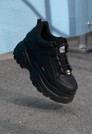 Sort chunky sneakers med kunstlædermateriale, fremtrædende snørebåndssystem, tyk sål og sølvlogo-accents på tungen og siden.