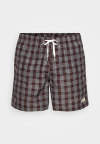 Καρό μαγιό σε μπορντό και μπλε. Κατασκευασμένα από ελαφρύ ύφασμα, με ελαστική μέση και λευκή κορδονιέρα, καθώς και μικρή ετικέτα λογότυπου.