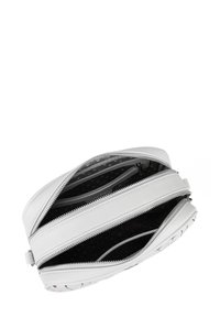 Bílá kožená taška s několika přihrádky, obsahující stříbrné zipové uzávěry a vnitřní vzor s puntíky. Plochý design a hladká textura.