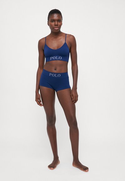 Marineblauw ondergoedset met een bralette en boyshorts, beide voorzien van het "POLO"-logo in lichtgrijs. Zacht materiaal en eenvoudig design.