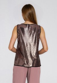 Bezrekawnik z brązowymi cekinami, z zaokrąglonym dekoltem, o gładkiej fakturze i kontrastującą czarną lamówką wzdłuż otworów na ramiona i na dole.