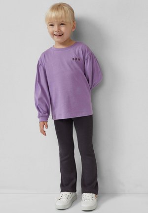 Paarse lange mouwen shirt met pofmouwen en bloemige borduursels; gecombineerd met donkergrijze broek en witte sneakers. Soepele stofstructuur.