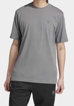 Szara bawełniana koszulka z krótkim rękawem, okrągłym dekoltem i małym, tonalnym logo Adidas na piersi. W połączeniu z ciemnymi spodniami.