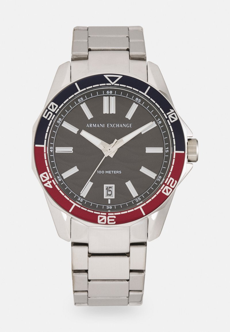 Silberner Edelstahl-Zeitmesser mit einem dunkelgrauen Ziffernblatt, rotem und blauem Lünettenring, auffälligen Stunden-Markierungen und einer Datumsanzeige auf der 6-Uhr-Position.