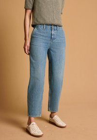 Jeans azzurri chiari a vita alta con una vestibilità comoda, realizzati in denim, caratterizzati da un classico design a cinque tasche e un risvolto, abbinati a sneakers color crema.